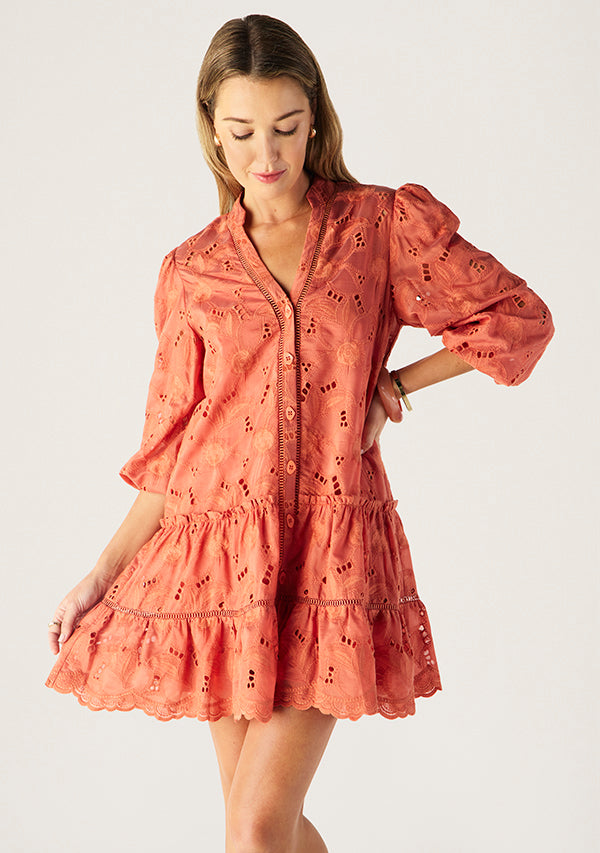 Woman wearing a coral lace dress on a white background