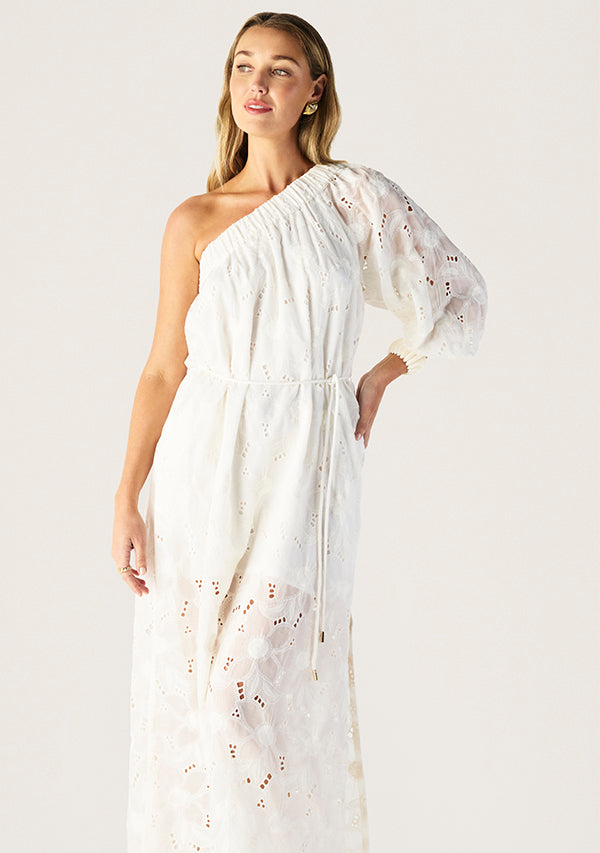 Woman wearing a white one-shoulder dress with floral details on a light background