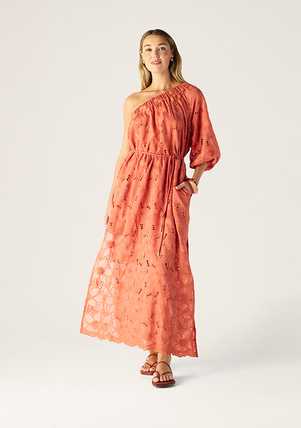 Woman wearing a one-shoulder pink dress with floral patterns on a white background