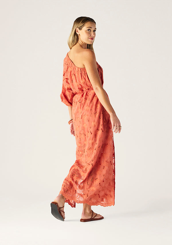 Woman wearing a coral dress with floral patterns on a white background