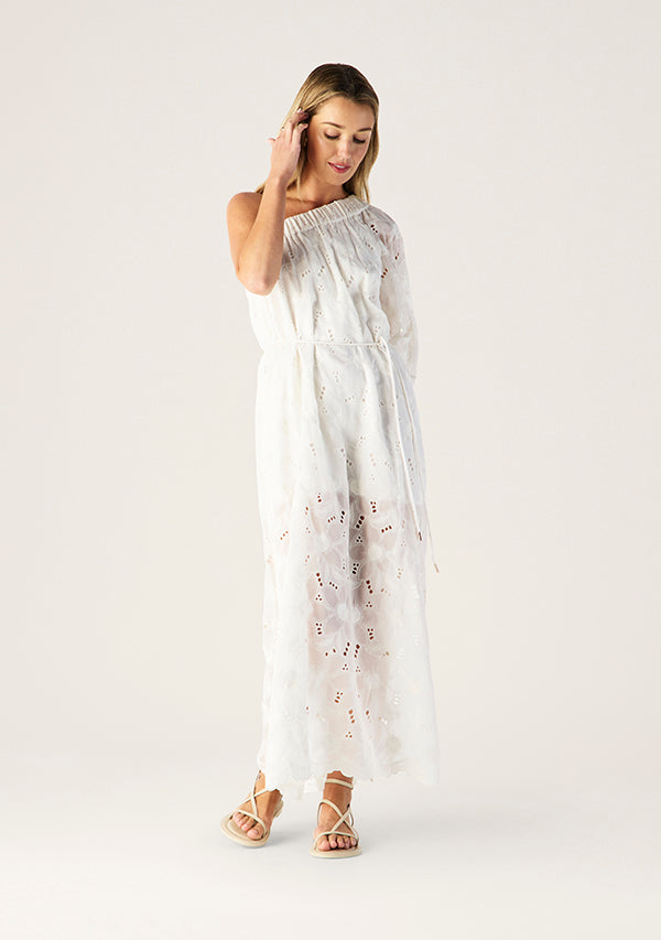 Woman wearing a white dress with floral patterns on a plain background